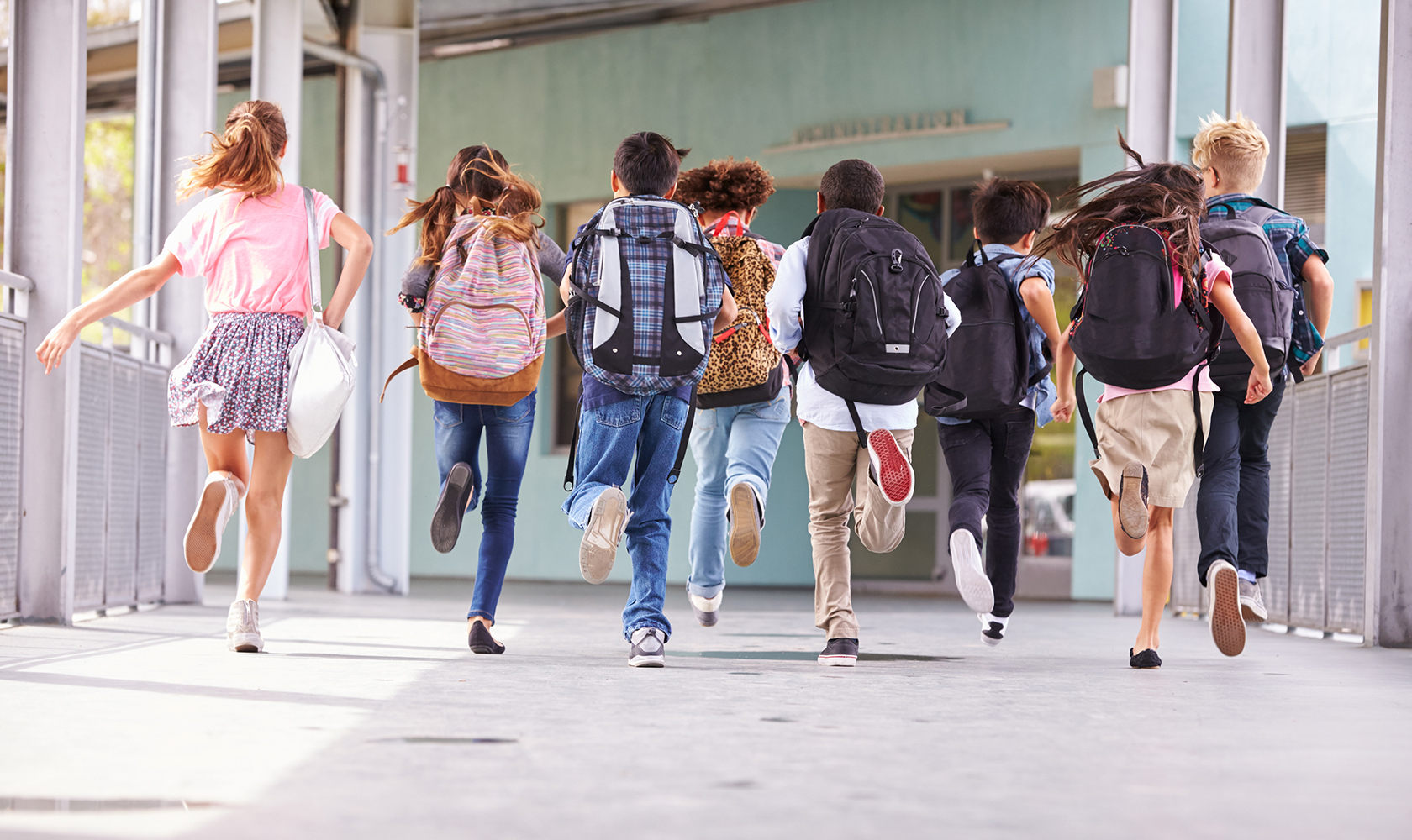 Group of elementary school kids running at school, back view