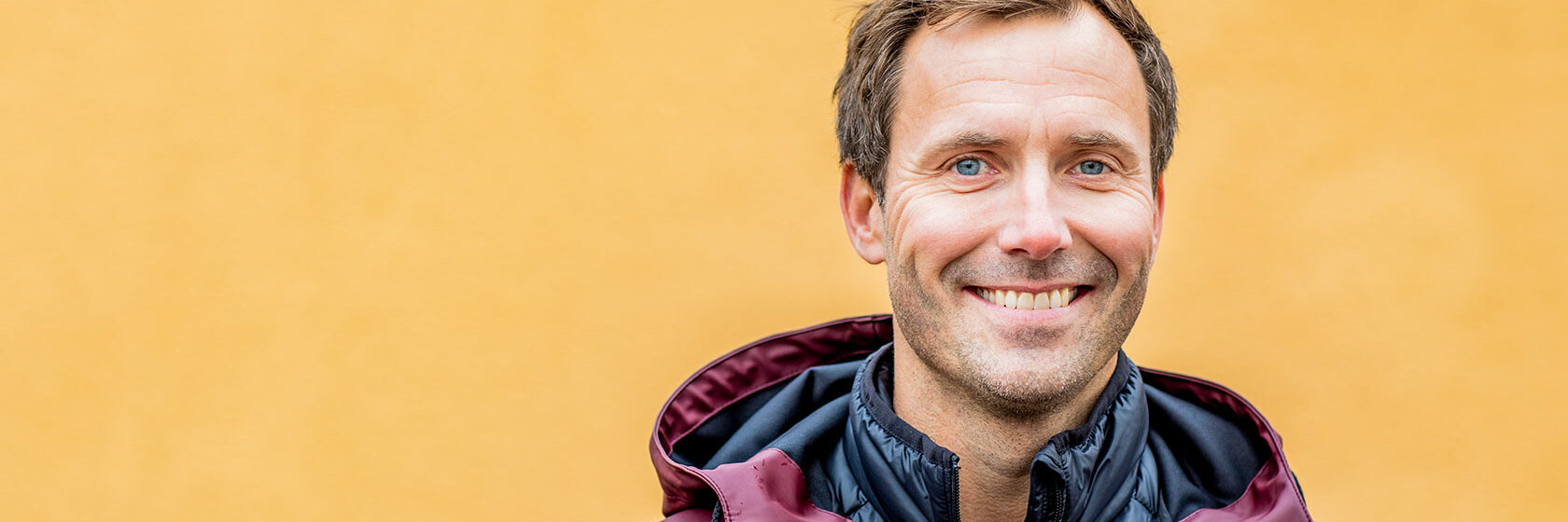 Man mot gul husvägg