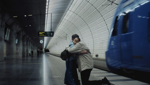 En pappa kramar om sitt barn på en tågperrong