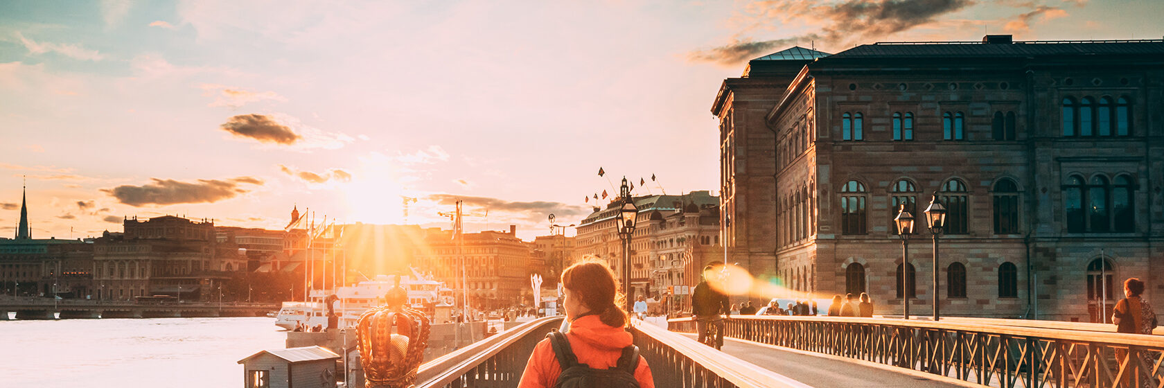 kvinna går i solen över Skeppsbron