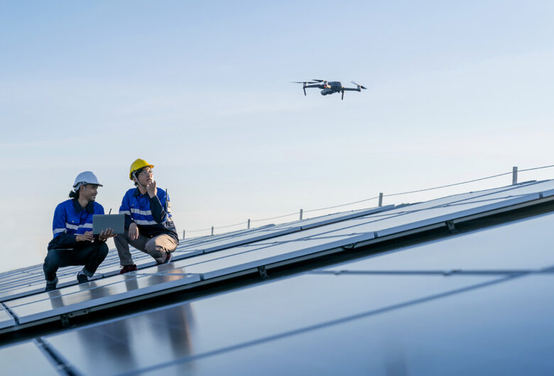 Två män på tak med solpaneler flyger drönare