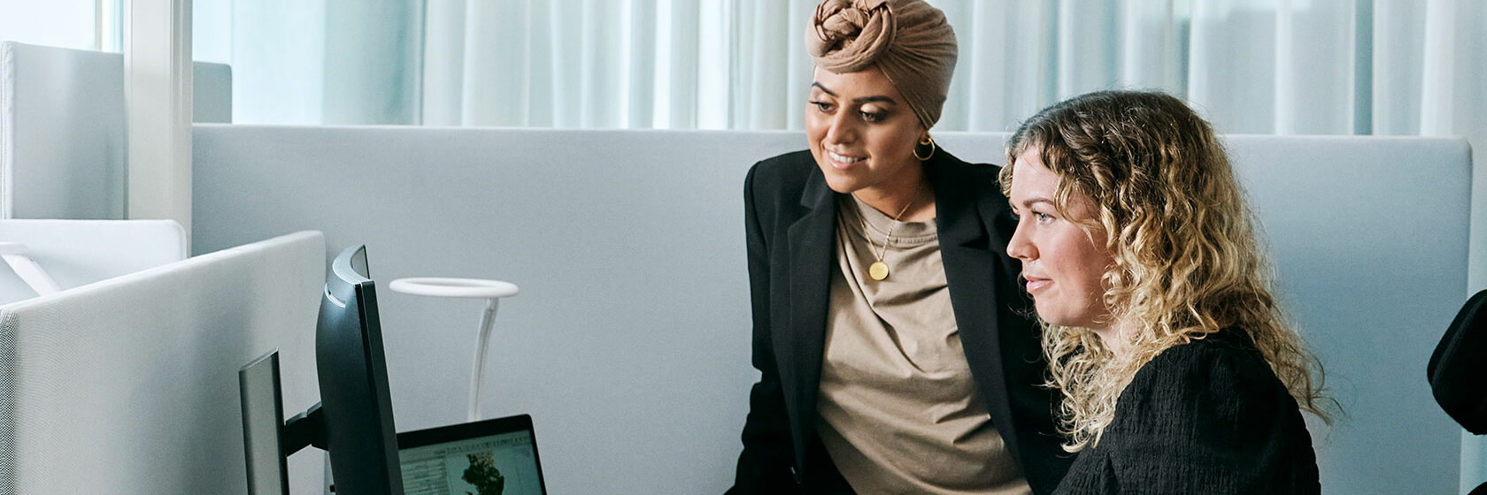 Två kvinnor tittar på en skärm vid arbetsplats