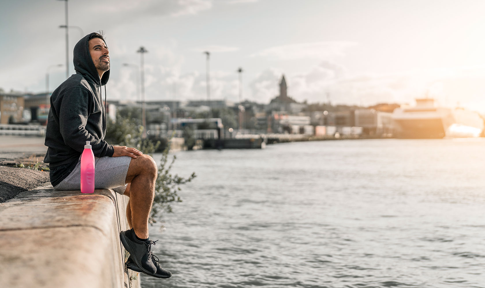 Man sittandes på kajkant i solnedgång