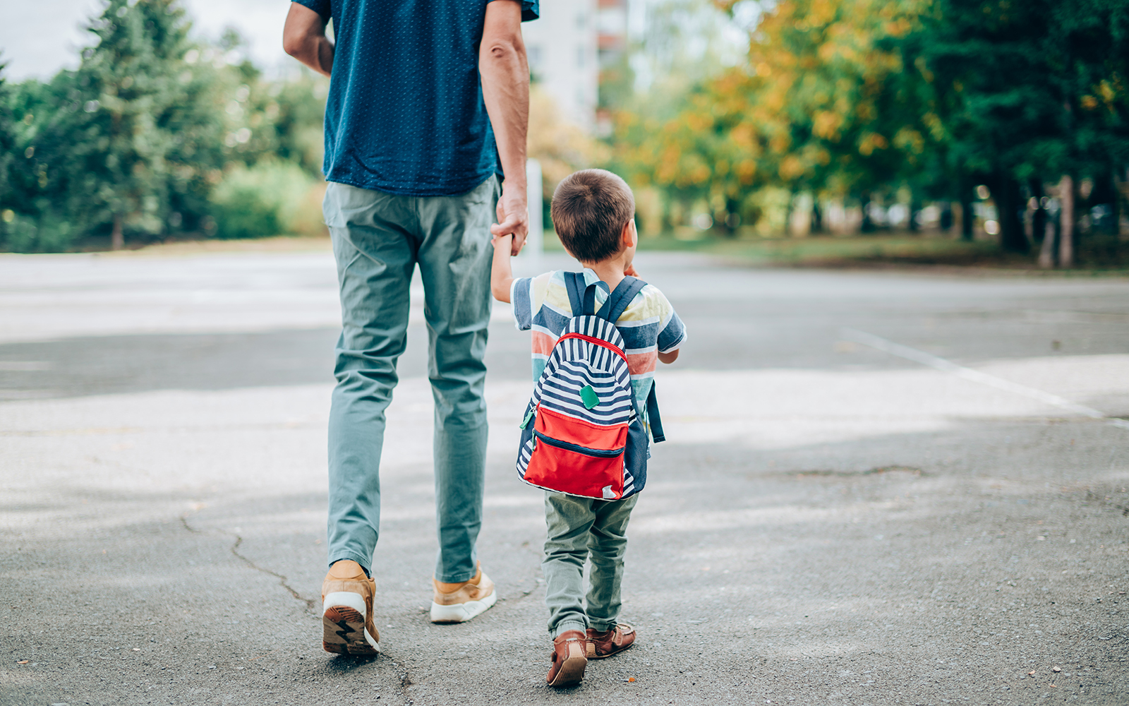 Pappa och son håller handen och promenerar