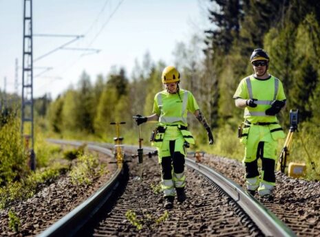 Två banarbetare går vid sidan av ett järnvägsspår