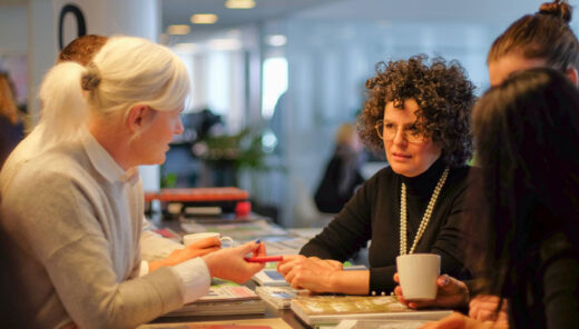 Två kvinnor i diskussion över ett bord i kontorsmiljö