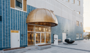 Entrén på Västerviks Nya psykiatrisjukhus med blå-vit fasad och en kopparkupol över entrén.