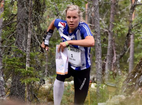 Sara Hagström springer genom skogen med karta i handen