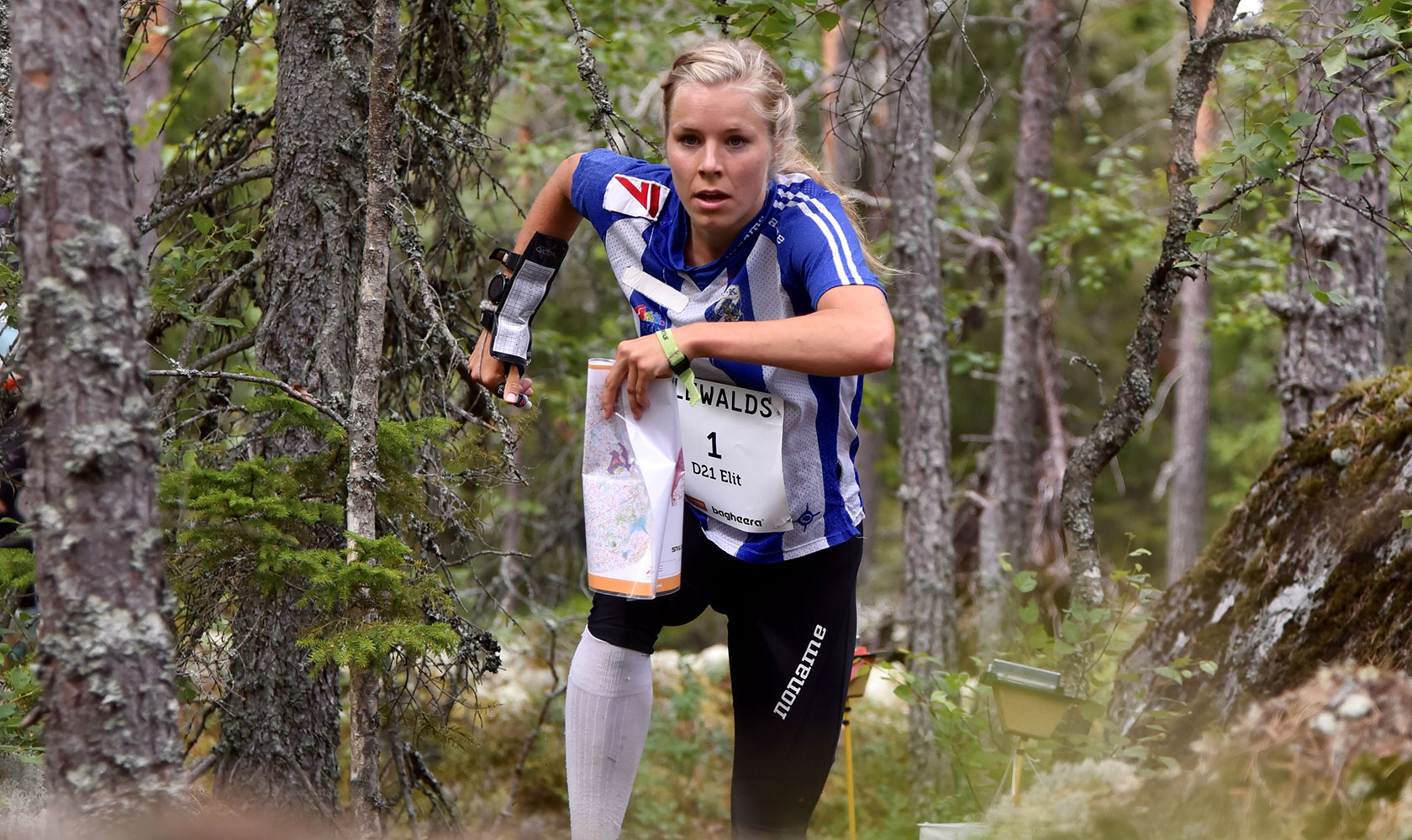 Sara Hagström springer genom skogen med karta i handen