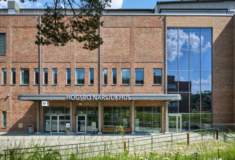 Högsbo Närsjukhus - byggnad med tegelväggar och glasfönster under en klarblå himmel.