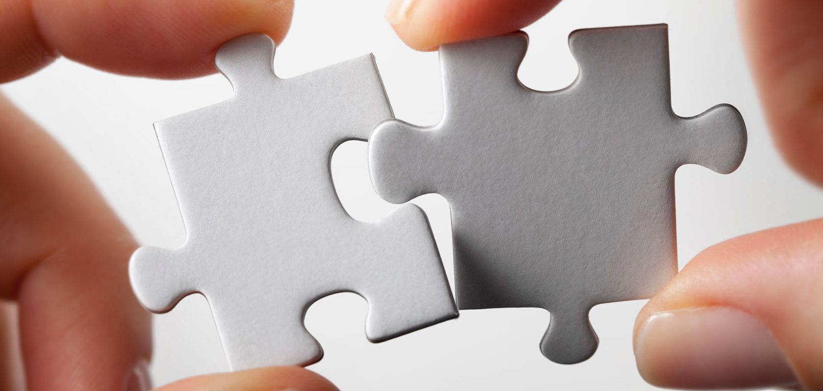 Två händer passar ihop två pusselbitar