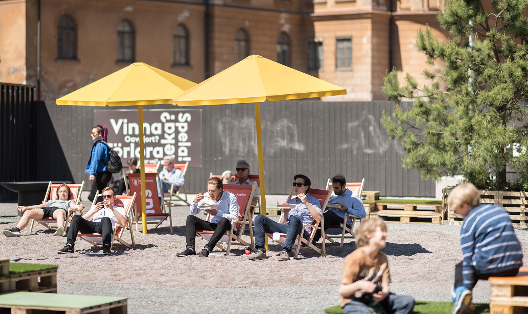 Människor i solstolar på ett torg