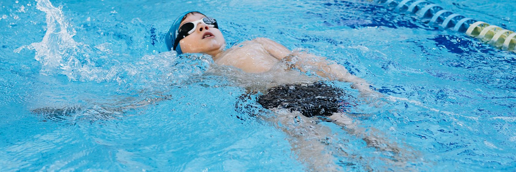 pojke simmar ryggsim i bassäng