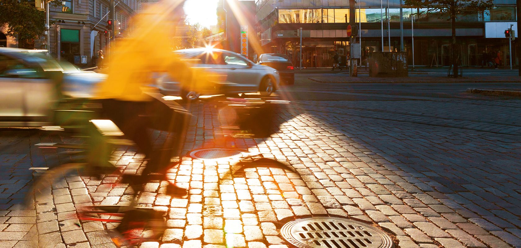 En cyklist i gul jacka cyklar på stenlagd gata