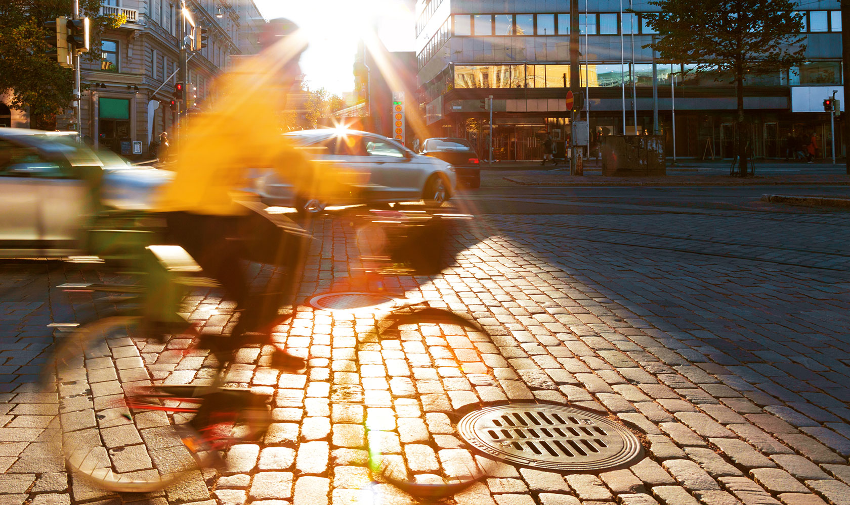 En cyklist i gul jacka cyklar på stenlagd gata
