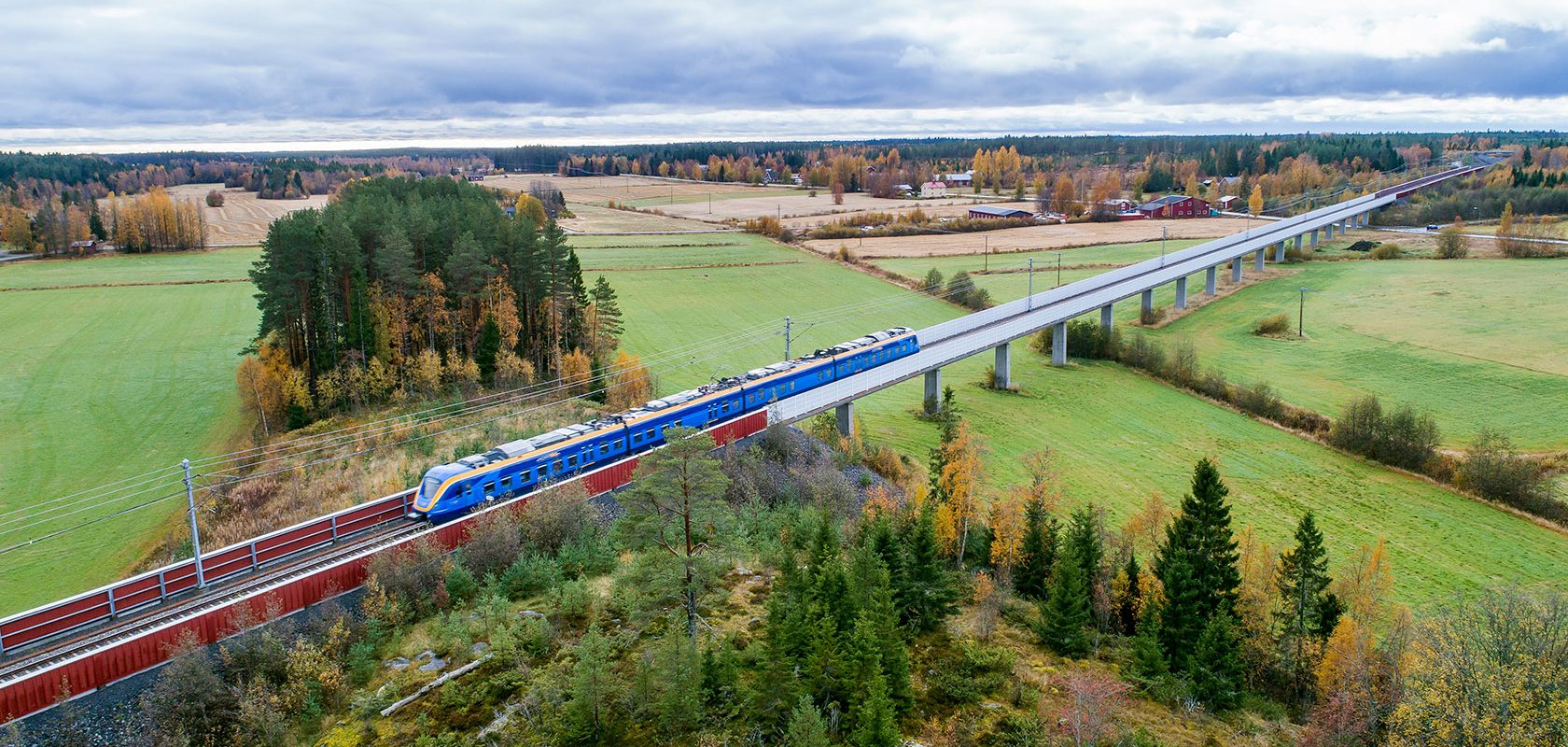 Ett tåg åker över en bro i ett grönt landskap