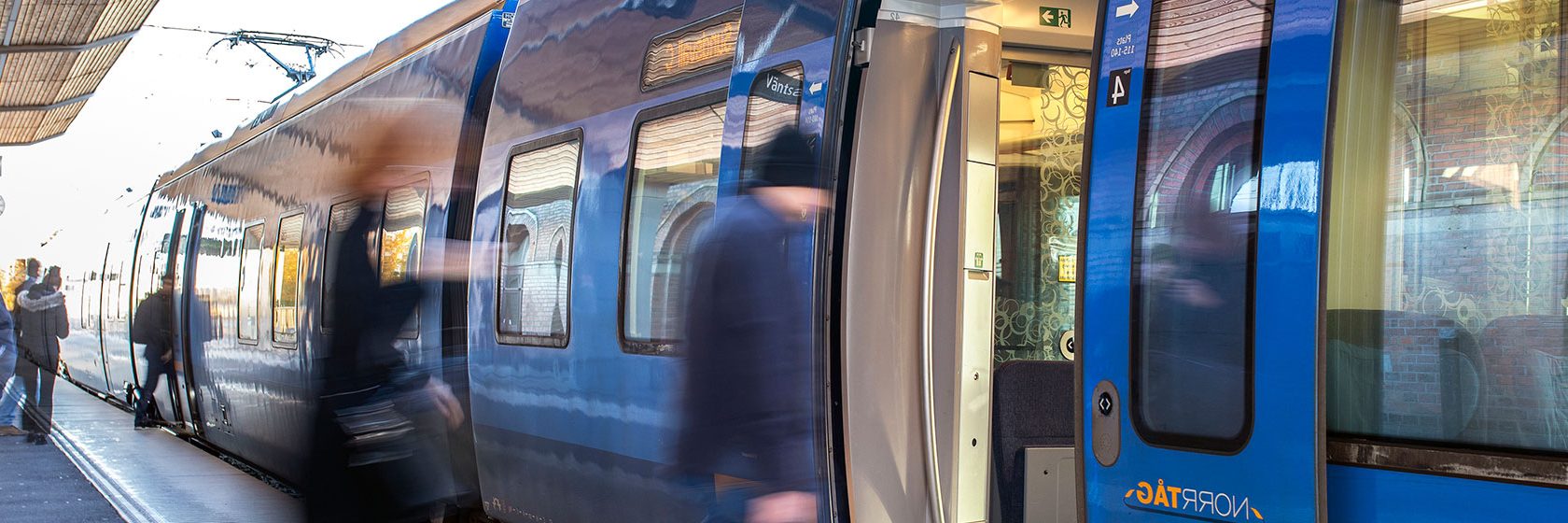 Människor kliver ombord på ett tåg från en perrong