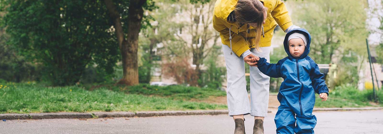 Kvinna håller barn med regnkläder i handen