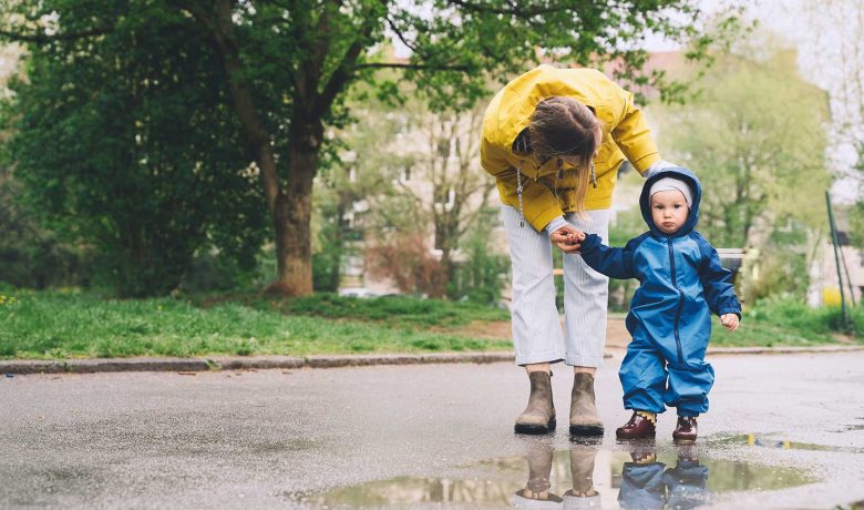 Kvinna håller barn med regnkläder i handen