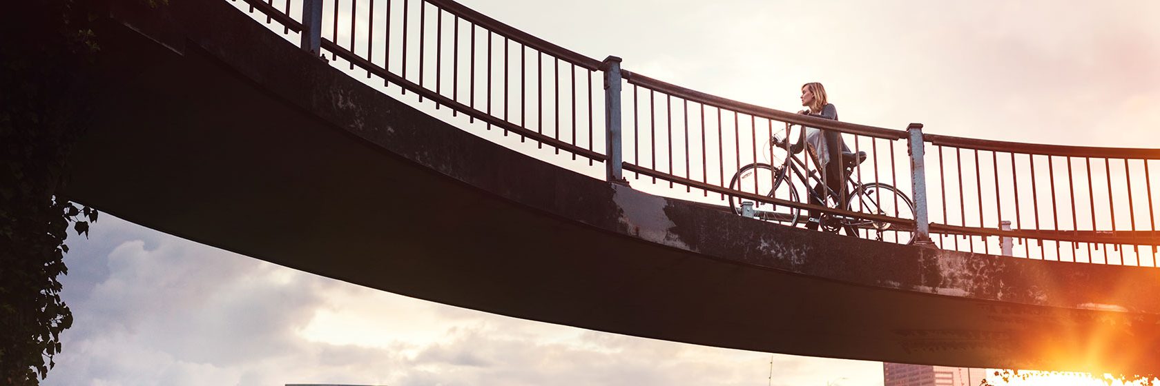 Kvinna cyklar över en bro
