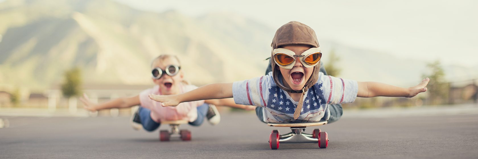 Två barn leker piloter med sina skateboards