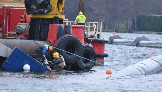 Dykare påväg ner i vattnet bredvid stor ledning som flyter i vattnet
