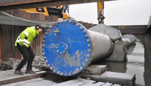 Man står och tittar på stort vattenledningsrör