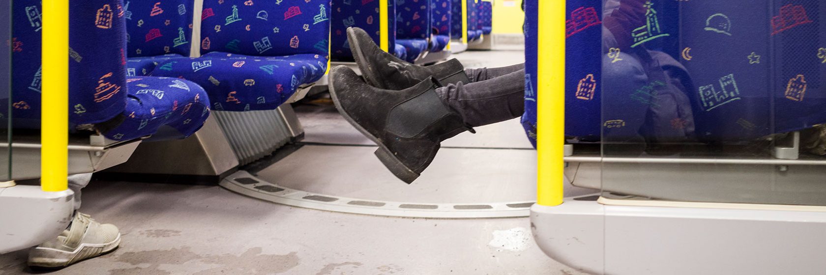 Ett par fötter sticker ut från tunnelbanesätet