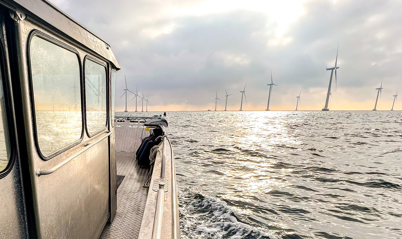 Båt på havet med vindkraftverk i förgrunden