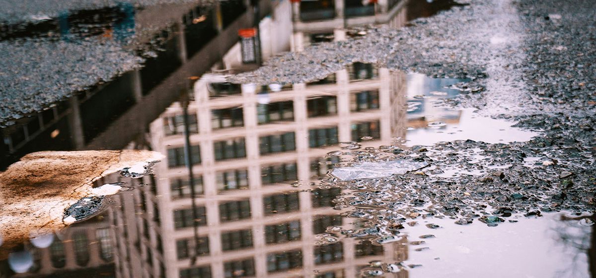 Spegling av hus i vattenpöl