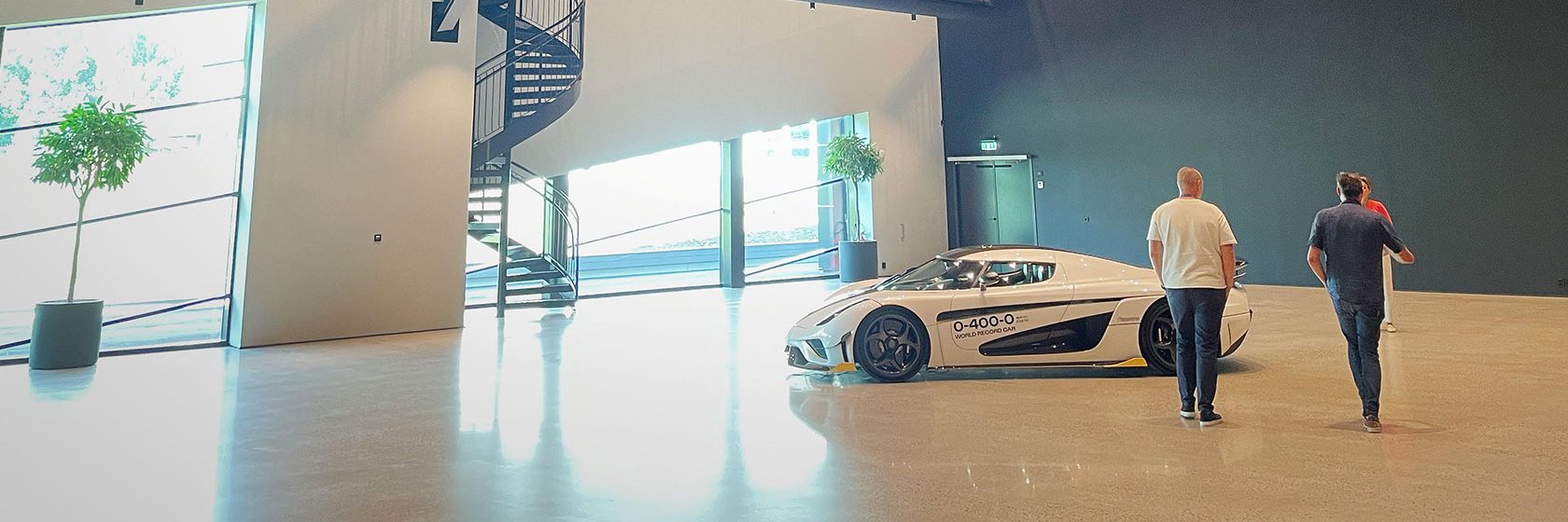 Showroom med vit sportbil på vitt golv