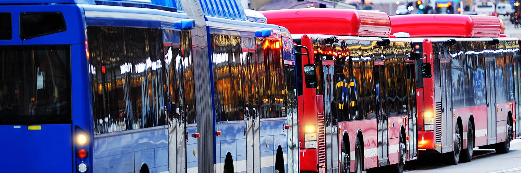 En blå och en röd buss på en gata