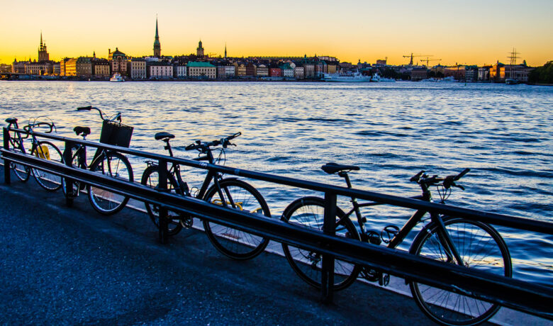 Cyklar står parkerade mot ett staket vid vattnet