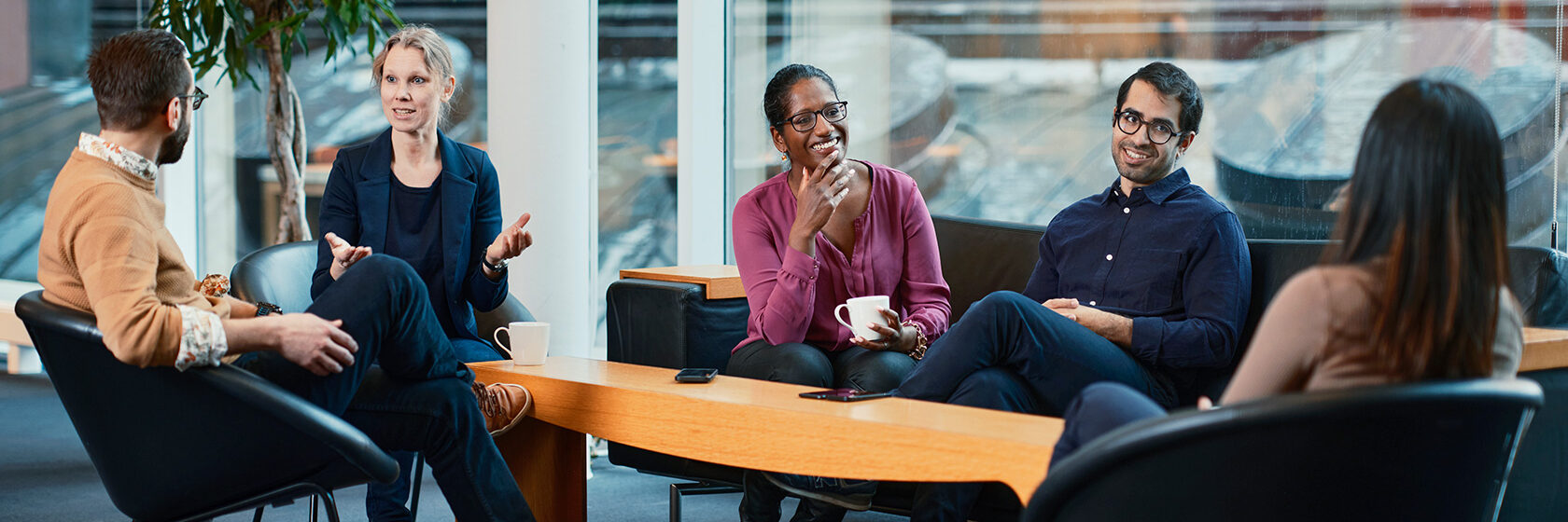 Två killar och tre tjejer sitter vid ett bord och pratar