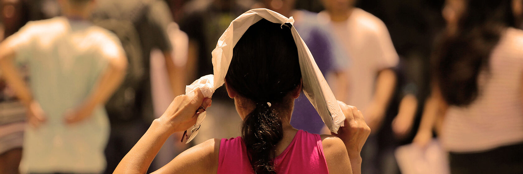 Kvinna med en handduk över huvudet. Gåendes i en stadsmiljö