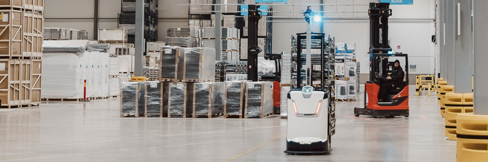 Inuti ett stort lager där man ser en truck och ett självkörande fordon