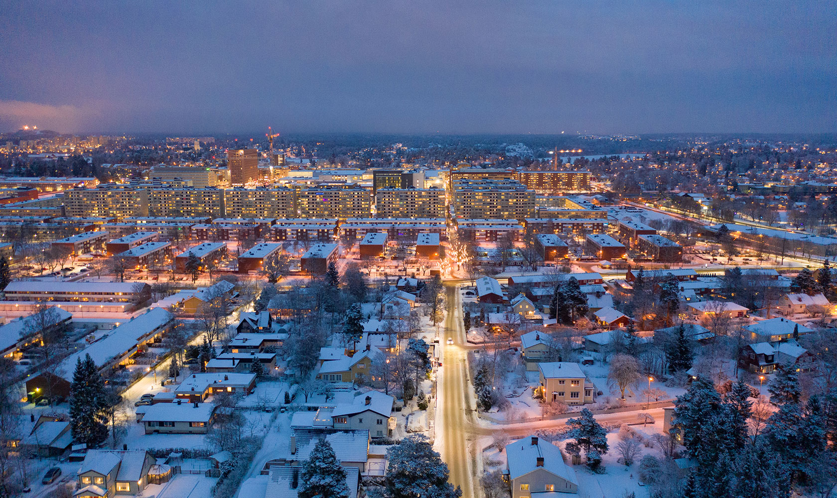 Vy över snöklädd stad i skymningsläge.