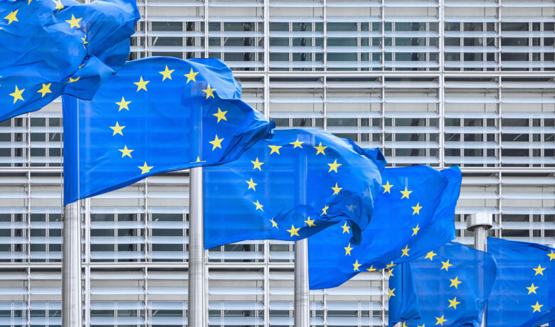 Sex EU-flaggor framför ljusgrå kontorsbyggnad