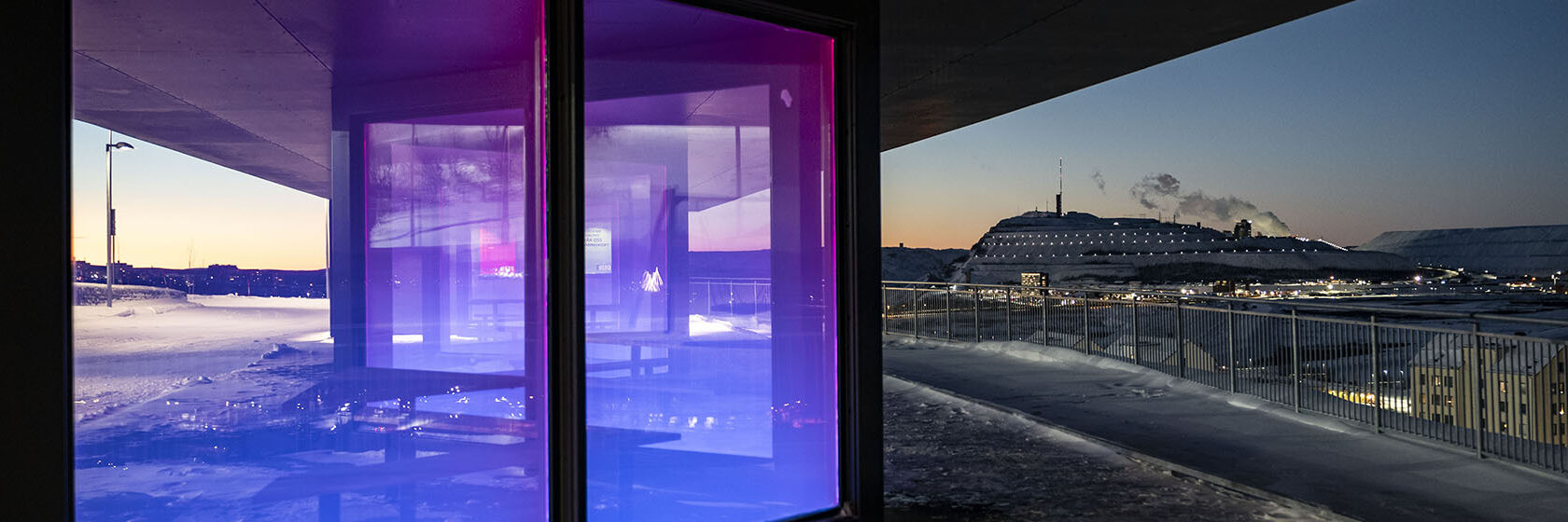 Rastplats belyst i lila och blått med Kiruna i bakgrunden