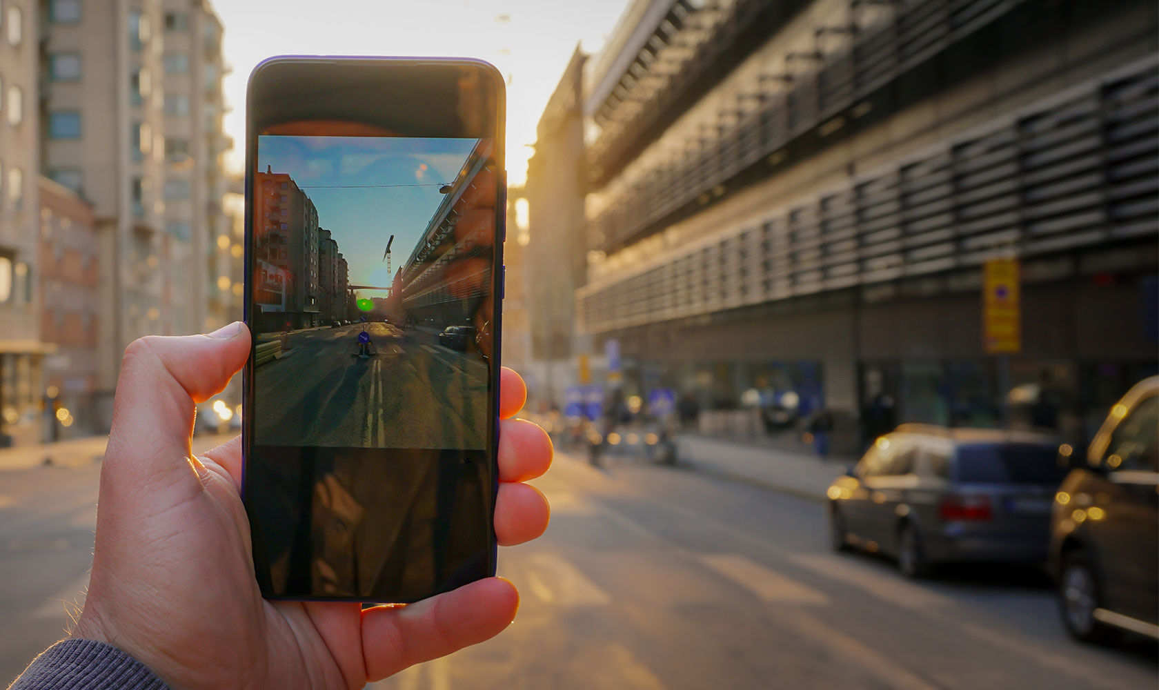 Beskuren hand som håller på mobil bakgrund mot stadsgatan
