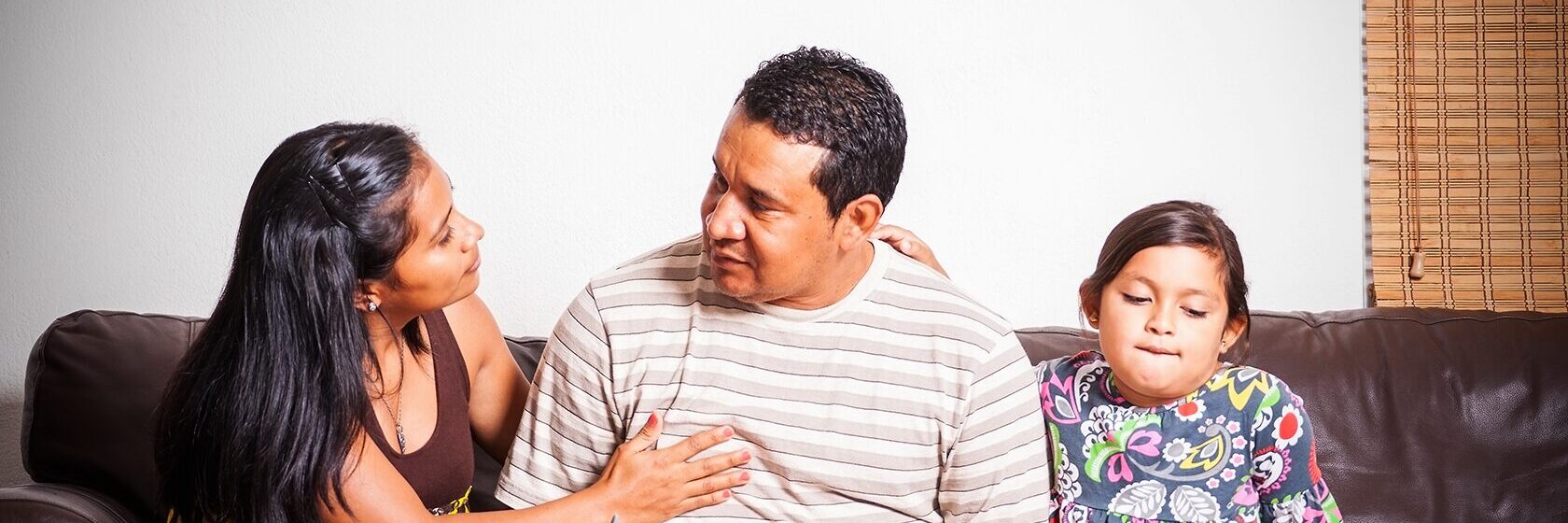 Familj med latinskt påbrå sitter i en soffa och diskuterar