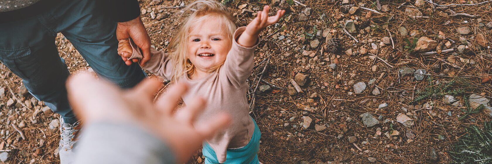 Familj utomhus som sträcker händer mot varandra