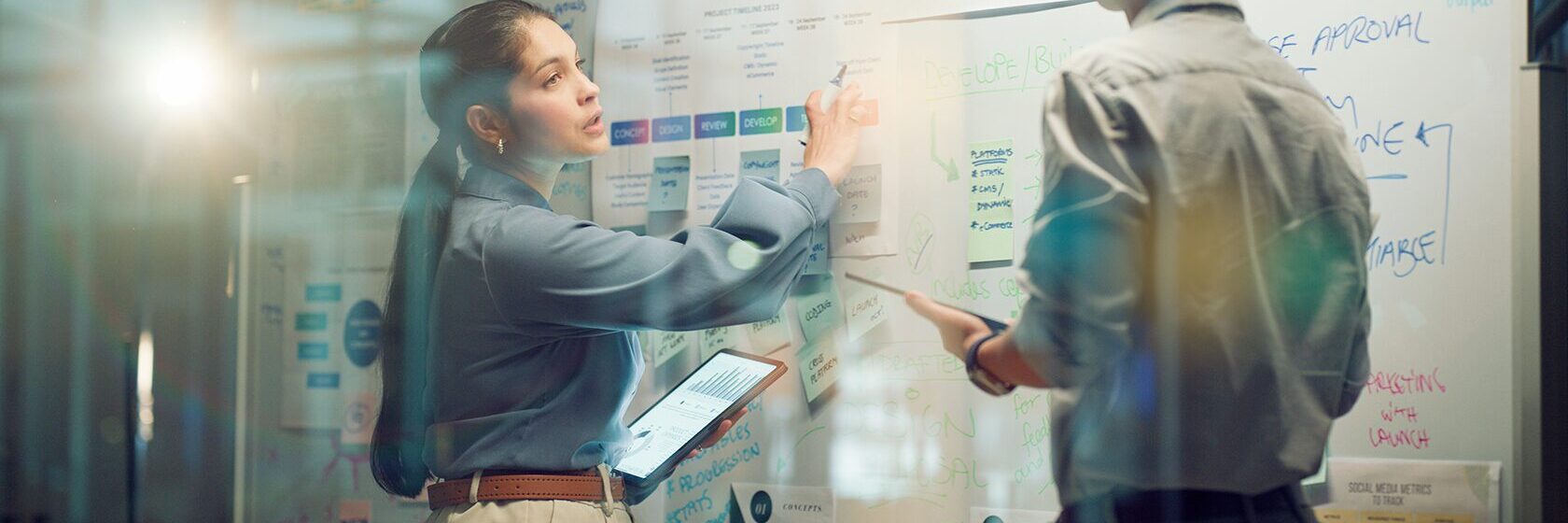 Två personer analyserar data på en vägg med analyser