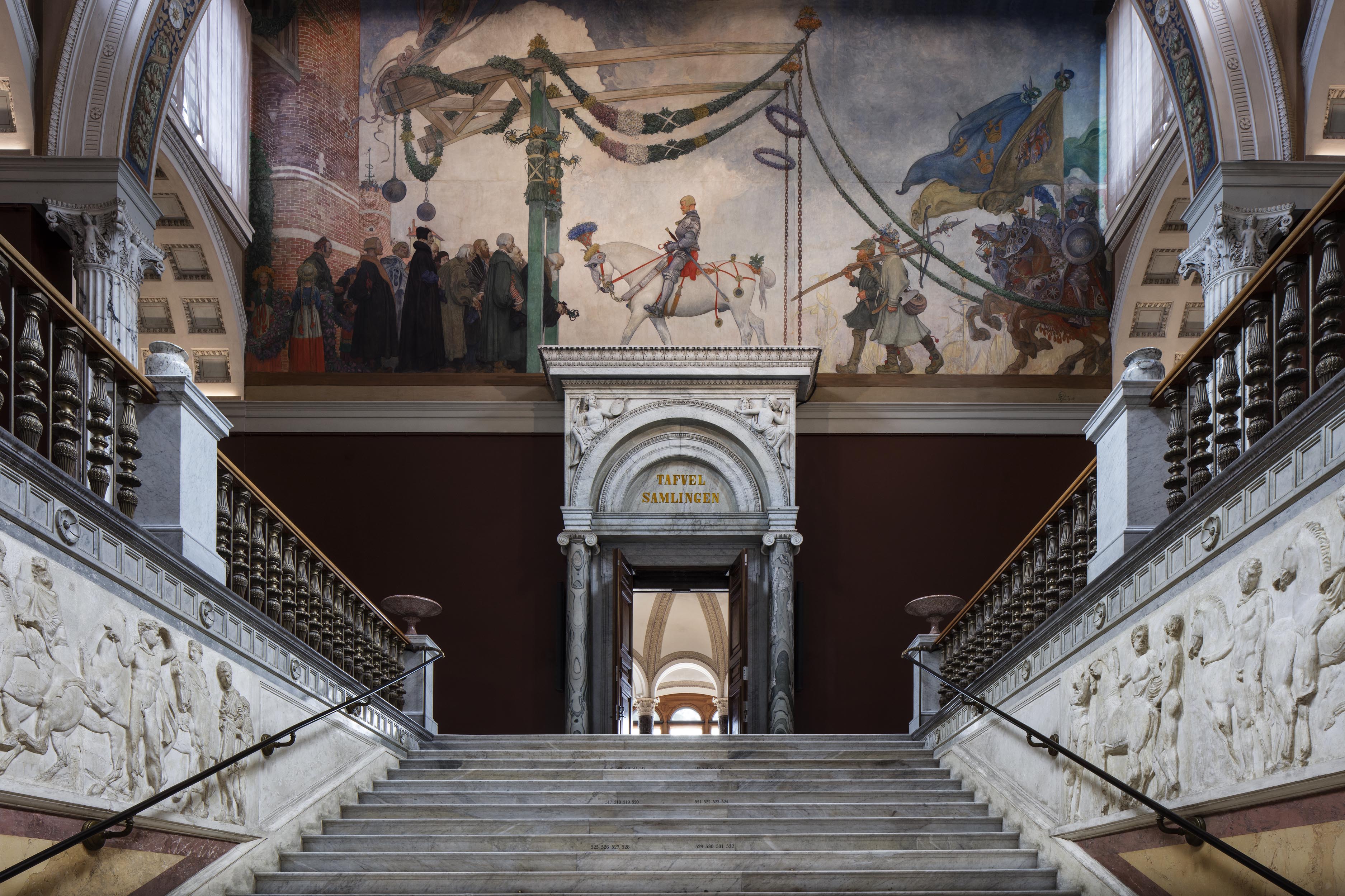 Marmorttäckt trappa med historiskt väggmålning ovanför dörren till konstsamlingen på museum.