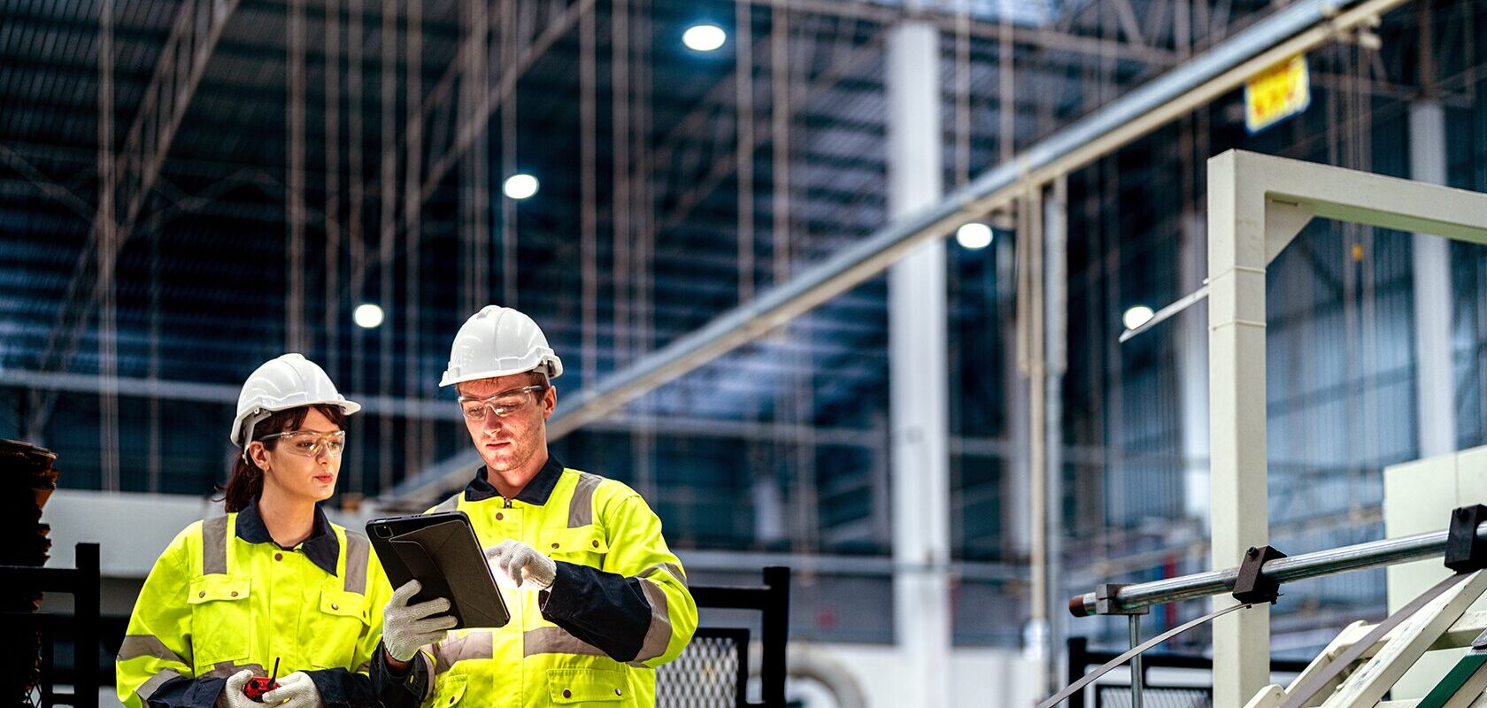 Två gulklädda industriarbetare i en industri