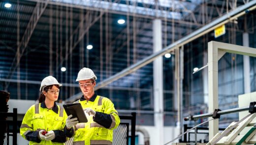 Två gulklädda industriarbetare i en industri