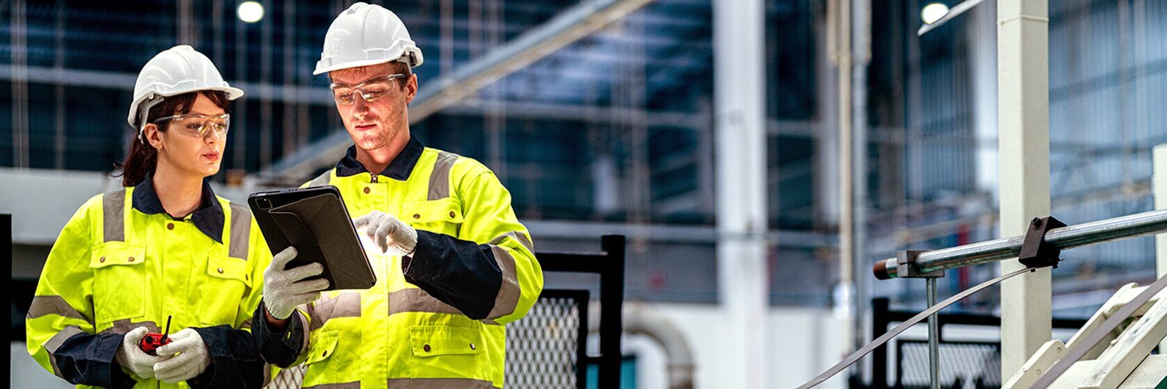 Två gulklädda industriarbetare i en industri