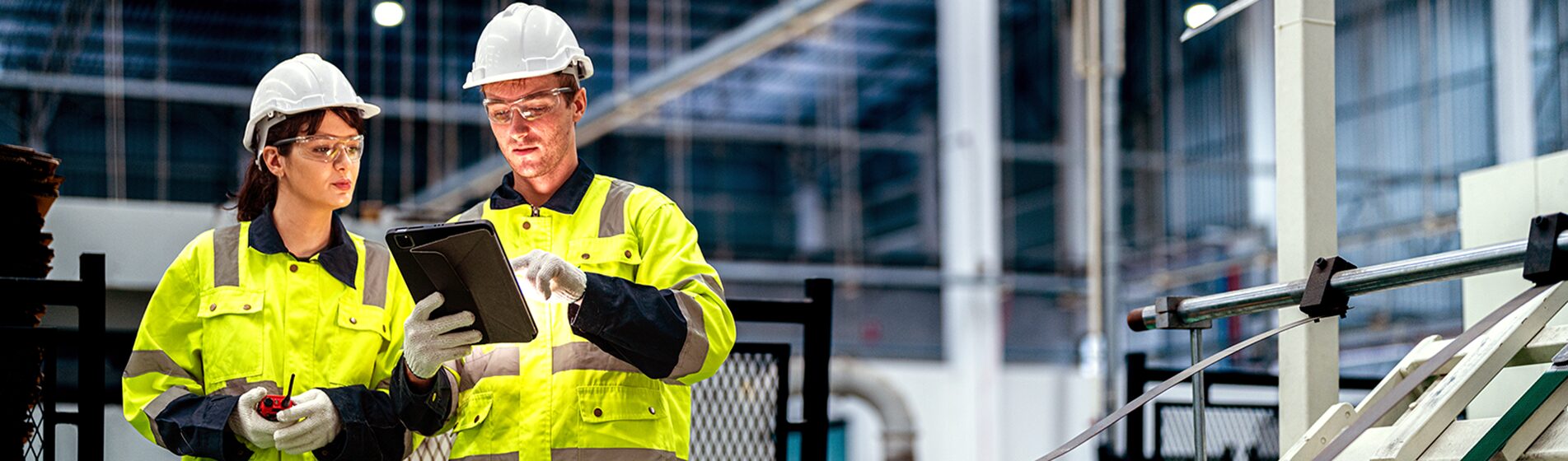 Två gulklädda industriarbetare i en industri