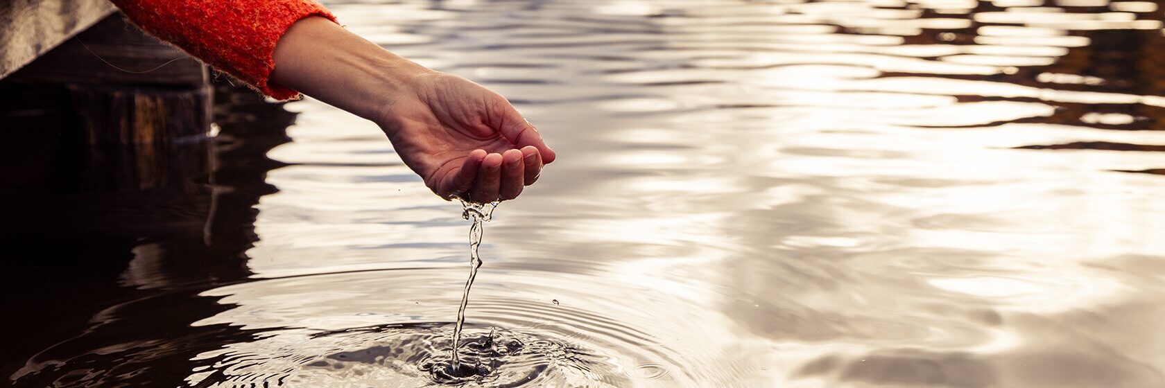 Hand som silar vatten vid en sjö