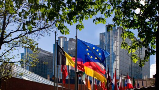 Flaggor framför EU-parlamentet i Bryssel inramat av träd